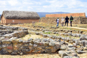 Visitantes en el yacimiento de Numancia junto a una de las viviendas recreadas.-ÁLVARO MARTÍNEZ