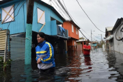 Dos personas caminan por una calle inundada en Juana Matos (Puerto Rico), el 21 de septiembre.-AFP / HECTOR RETAMAL
