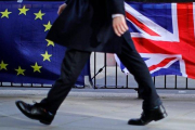 Un hombre camina junto a una bandera de la UE y otra del Reino Unido, en Londres.-TOLGA AKMEN (AFP)