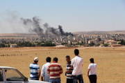 Gente mira el humo de los combates en Kobane desde la frontera turca.-Foto: AFP / STRINGER