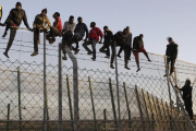 Policías españoles tratan de disuadir a inmigrantes encaramados a la valla de Melilla, fronteriza con Marruecos.-EFE / FRANCISCO G. GUERRERO