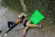 Dos de las víctimas en el suelo, junto a un cartel que les acusa de ladrones, firmado por un grupo de justicieros, este lunes en Guadalajara (México).-EFE