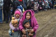 Unos niños sirios esperan junto a otros refugiados para cruzar la frontera entre Macedonia y Serbia.-/ AFP / ARMEND NIMANI