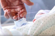 Un bebé recién nacido coge la mano de uno de sus padres. HDS