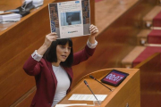 Sandra Miguez muestra, en el pleno de las Corts, un tuit del grupo popular en el que se hace eco del titular de una entrevista a un profesor, criticado por la diputada de Podemos durante su intervención.-MIGUEL LORENZO