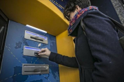 Una clienta bancaria utiliza su tarjeta en un cajero automático-JOAN CORTADELLAS