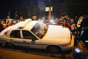 Vecinos de Ferguson golpean un coche de policía, el martes durante las protestas.-Foto: AFP / SCOTT OLSON