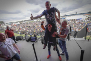 Marc Márquez levanta sobre sus hombros al aficionado que pujó, en la subasta solidaria de Silverstone, por hacerse un selfie con él. /-MOTOGP.COM / DIEGO SPERANI