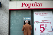 Un hombre saca dinero de un cajero del Popular en Madrid.-REUTERS / ANDREA COMAS