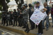 Policías venezolanos vigilan durante las protestas en contra de Nicolás Maduro.-AP