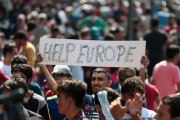 Un inmigrante se manifiesta este jueves en Budapest con una pancarta en la que se lee "Ayúdanos Europa".-AFP / FERENC ISZA