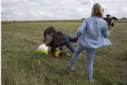 Petra Laszlo le hace la zancadilla a un padre que lleva en brazos a su hijo y una bolsa con sus pertenencias, en Roszke (Hungría).-MARKO DJURICA / REUTERS