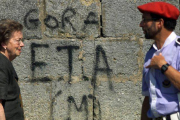 Una mujer y un erzaina pasan ante una pintada en favor de ETA.-ARCHIVO