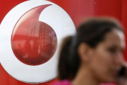 Una mujer habla por móvil frente a un anuncio de Vodafone.-REUTERS