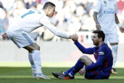 Cristiano ayuda a Messi a levantarse tras una falta que le cometieron en un clásico jugado en Madrid el 2017.-AP
