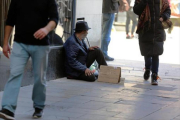 Un indigente pide ayuda a los traseúntes en una calle de Barcelona, ayer.-/ RICARD CUGAT