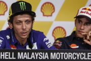 Valentino Rossi explica sus sensaciones antes del Gran Premio de Malasia, bajo la atenta mirada de Marc Márquez.-AP / JOSHUA PAUL