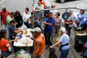 Venezolanos hacen cola para pagar la fruta y las verduras en un mercado callejero, en Caracas, el 13 de noviembre.-REUTERS / MARCO BELLO