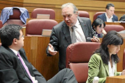 El procurador socialista José Francisco Martín (de pie) conversa con Óscar López durante el pleno. / ICAL-