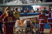 Los inmigrantes supervivientes de un naufragio llegan este jueves a tierra firme tras ser salvados por las autoridades de Libia, mientras los equipos médicos se llevan los cuerpos de los fallecidos.-REX SHUTTERSTOCK/ANTONIO MELITA