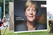 Retirada de un cartel electoral de Angela Merkel en Berlín-REUTERS / CHRISTIAN MANG