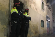 Dos mossos ante el portal de la calle de la Riera Alta donde se ha cometido el crimen.-/ GUILLEM SÀNCHEZ