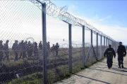 Policías húngaros vigilan a refugiados tras una valla temporal en la frontera con Serbia, cerca de Morahalom, el 22 de febrero del 2016.-ZOLTAN GERGELY KELEMEN