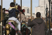 Unos niños montan en un tiovivo en presencia de adultos, en Madrid.-DAVID CASTRO