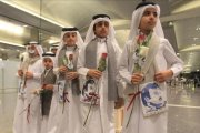Niños qatarís con flores e imágenes del emir Al Thani reciben a ciudadanos de Kuwait y Omán, países que no se han sumado al boicot, en el aeropuerto de Doha.-REUTERS / NASEEM ZEITOON