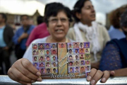 Una mujer muestra la foto de los estudiantes de Ayotzinapa.-AFP / YURI CORTEZ