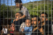 Refugiados e inmigrantes esperan tras una verja, en un campo de fútbol, a poder ser registrados, en Mitilene, este martes.-AP / SANTI PALACIOS