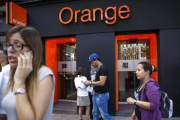 Personas pasan por delante de una tienda de Orange en Madrid.-