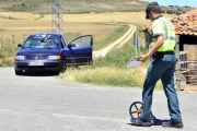 Un agente toma mediciones ante el turismo implicado en el accidente. / ÁLVARO MARTÍNEZ-