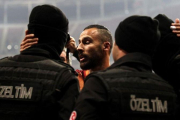 Yasin Oztekin se abraza a dos policías en el estadio del Galatasaray.-AFP