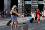 Turistas con sus equipajes pasan por delante de la tienda Tiffany en el paseo de Gràcia.-FERRAN NADEU