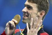 Phelps muestra su medalla señalando los cuatro oros que ha conseguido hasta ahora.-MICHAEL DALDER / REUTERS