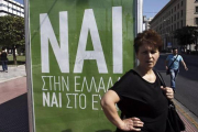 Una mujer espera el autobús junto a un cartel que pide el voto positivo en el referéndum, en el que se lee: "Sí a Grecia, sí al euro".-Foto:   EFE / YANNIS KOLESIDIS