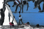 Unos inmigrantes tratan de sacar a un niño del mar frente a las costas de Libia, en una foto de archivo.-ARIS MESSINIS