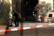 Un agente examina la mochila en la que el autor del ataque llevaba los explosivos, frente a un restaurante de Ansbach (Alemania), este domingo.-AP / MATTHIAS SCHRADER