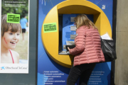 Una mujer saca dinero del cajero automático.-MÓNICA TUDELA
