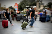 Una pareja con sus maletas y mochilas, ayer en una calle de Barcelona.-FERRAN NADEU