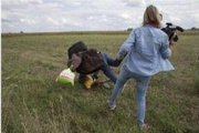 Petra Laszlo le hace la zancadilla a un padre que lleva en brazos a su hijo y una bolsa con sus pertenencias, en Roszke (Hungría).-MARKO DJURICA / REUTERS