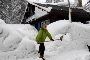 Una mujer limpia la nieve de los accesos a su casa en Val dIsere, en los Alpes franceses.-AFP / JEAN-PIERRE CLATOT