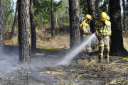 Bomberos refrescando una zona quemada. / VALENTÍN GUISANDE-