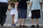 Tres generaciones de ciudadanos a la espera de cruzar una acera.-JULIO CARBO