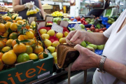 Una mujer llena la cesta de la compra en un mercado de Barcelona.-FERRAN NADEU