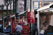 Un hombre pasa junto a un cartel electoral de Meïmarakis (derecha) y otro de Tsipras (arriba), este miércoles en Atenas.-AFP/LOUISA GOULIAMAKI
