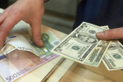 Euros y dólares en las manos.-AFP / ARCHIVO