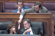 Mariano Rajoy y Soraya Sáenz de Santamaría hablan en el banco azul mientras Rafael Hernando les pasa una nota.-DAVID CASTRO