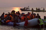 Varios voluntarios ayudan a refugiados a su llegada en un atestado bote neumático a Lesbos, el 20 de marzo.-AP / PETROS GIANNAKOURIS